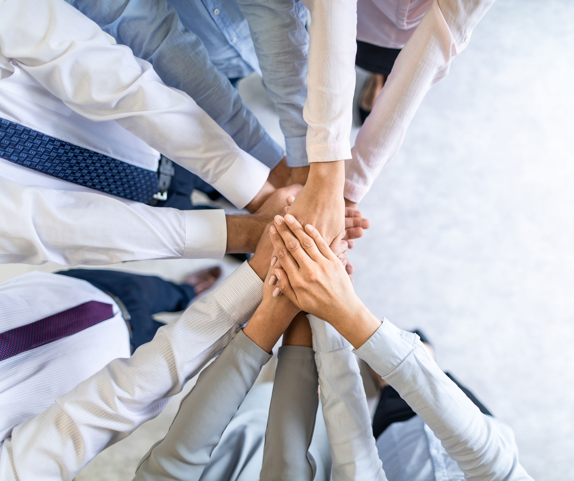 Eine Gruppe von Geschäftsleuten, die ihre Fäuste auf einem Tisch zusammenlegen - Teamwork.